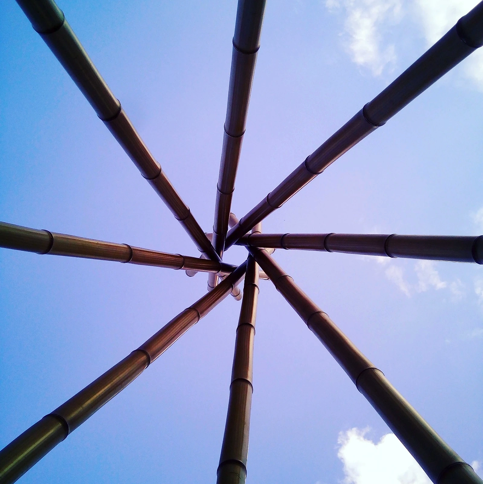 Vista hacia arriba del encuentro radial de los elementos de bambú, con el cielo al fondo